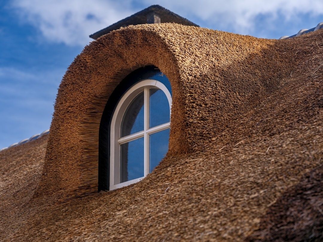 Nahaufnahme eines traditionellen Reetdachs mit rundbogigem Fenster